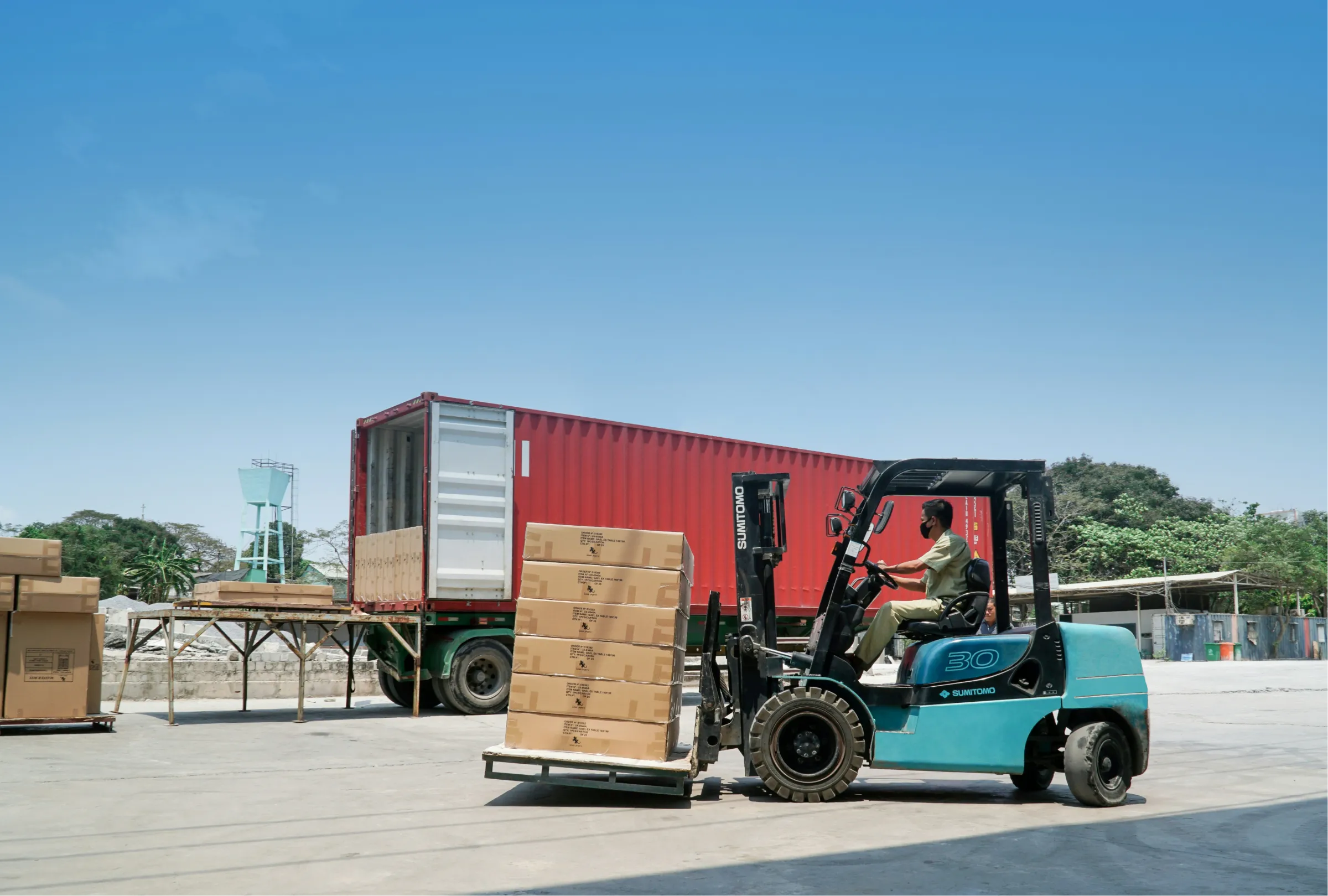 Forklift loading a shipping container at the dock